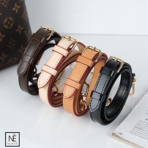 May include: Four leather purse straps in brown, cream, tan, and black, each with gold-colored metal hardware. The straps are arranged in a row, with a patterned purse visible in the background. The brand logo "NURVÈ" is in the lower left corner.