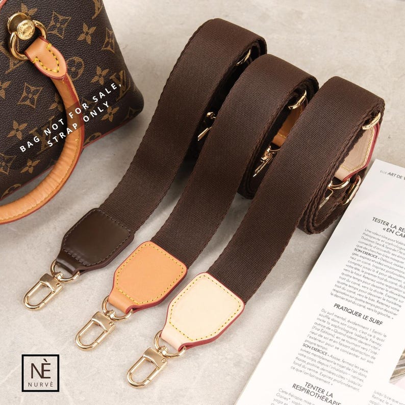 May include: Three brown handbag straps with gold-coloured clasps and leather details. The straps are made of a strong fabric and are designed to attach to a handbag. The image also shows a portion of a brown and tan handbag.