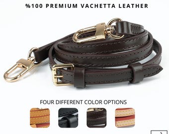 May include: A dark brown leather purse strap with gold-colored hardware, including clasps and a buckle. The strap is coiled and features stitching along the edges. The text reads '%100 PREMIUM VACHETTA LEATHER' and 'FOUR DIFFERENT COLOR OPTIONS'.