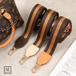 May include: Three brown and tan striped bag straps with gold-tone clasps. The straps have leather accents in brown, cream, and tan. The image also shows a brown handbag and the text "BAG NOT FOR SALE, STRAP ONLY."