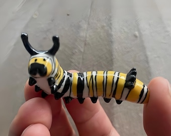 Miniatura de lagarta-monarca, criatura da floresta feita à mão em cerâmica, perfeita para prateleiras com estilo cottagecore e decoração inspirada na natureza.