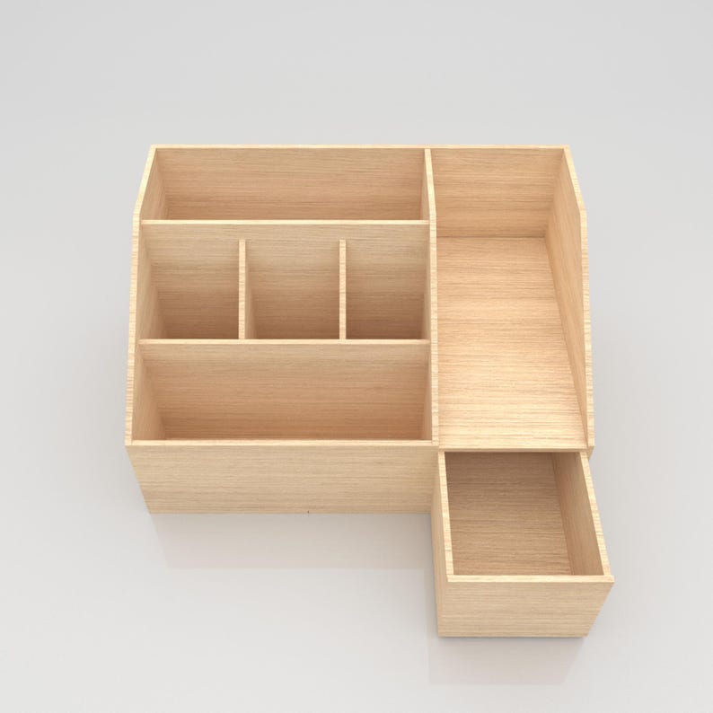 May include: A light-colored wooden desk organizer with multiple compartments and a drawer. The organizer has a rectangular shape with various sized sections for storage. The wood grain is visible, giving it a natural look.