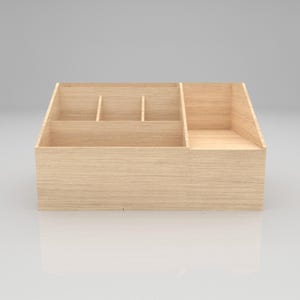 May include: A light-colored wooden desk organizer with multiple compartments. The organizer has a rectangular shape with a sloped side and several dividers to create separate storage spaces. The wood grain is visible, giving it a natural look.