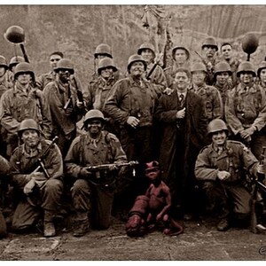 Può includere: Fotografia in seppia di un gruppo di soldati in uniforme, alcuni inginocchiati e altri in piedi, che posano per una foto. L'immagine include una grafica rossa di un pugno e il testo "Oct 10, 1944 Scotland".