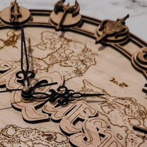 May include: A wooden clock with a map of the world and the word "EverQuest" in a decorative font. The clock has a black metal hand and a gold metal knob. The clock is surrounded by 12 decorative wooden pieces.