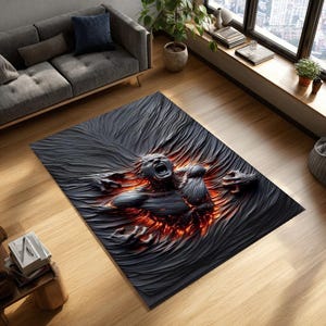 Op de afbeelding: Een rechthoekig zwart tapijt met een 3D-ontwerp van een schreeuwende figuur die uit een getextureerd oppervlak komt. De figuur is donker met rode en oranje accenten, wat een dramatisch effect creëert. Het tapijt ligt op een houten vloer.