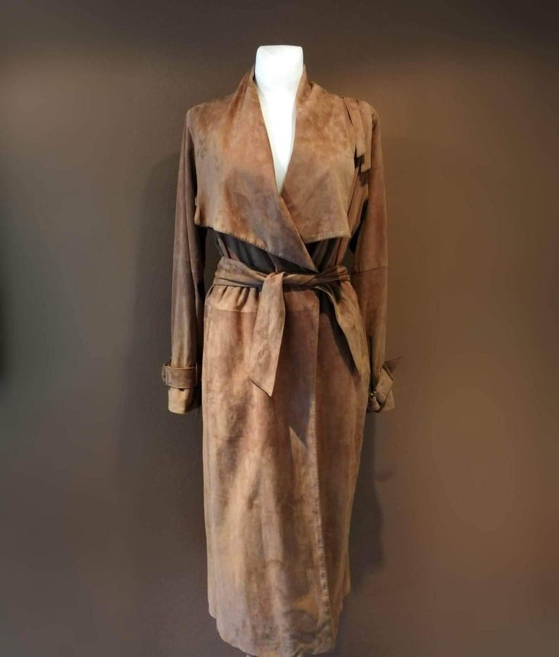 May include: A long brown suede coat with a wrap style collar and a tie belt.