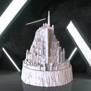 May include: A white detailed model of a large, multi-level castle with a tall spire on top. The castle is on a rocky base and appears to be made of stone.