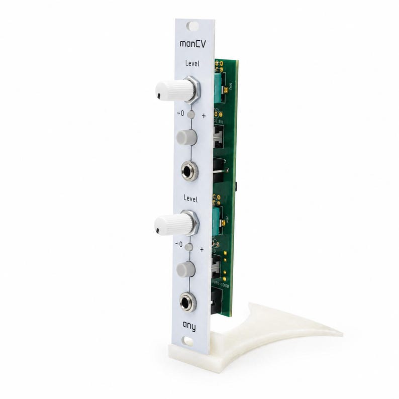 May include: A white modular synthesizer panel labeled manCV and any, featuring two white knobs, two grey buttons, and two metal input jacks. The vertical panel is attached to a green circuit board with visible electronic components.