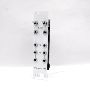 Pu&ograve; includere: Un modulo elettronico bianco con due interruttori a levetta e pi&ugrave; prese di ingresso. Il modulo presenta il testo "Switch", "Y2", "Y1", "X" e "any:switches". Sul lato destro &egrave; visibile una scheda a circuito stampato nera.