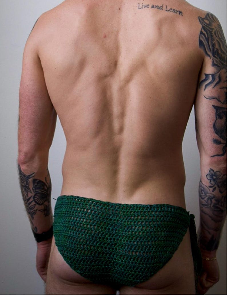 K&ouml;nnte beinhalten: Ein dunkelgr&uuml;nes H&auml;kel-Bikiniunterteil mit einer texturierten, handgestrickten Garnkonstruktion und seitlichen Bindeb&auml;ndern. Das Kleidungsst&uuml;ck ist aus tiefgr&uuml;nem Garn gefertigt und weist ein durchgehend gleichm&auml;&szlig;iges, dichtes Webmuster auf.