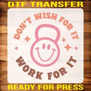 May include: A white background with a pink and orange circle with the text "Don't Wish For It Work For It" around the outside. Inside the circle is a pink kettlebell with a smiley face. The text "Ready For Press" is at the bottom of the image.