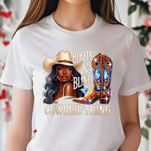 K&ouml;nnte beinhalten: Wei&szlig;es T-Shirt mit einer Grafik einer Frau mit Cowboyhut, einem verzierten Cowboy-Stiefel und dem Text "Boots & Bling. It's a Cowgirl Thing."