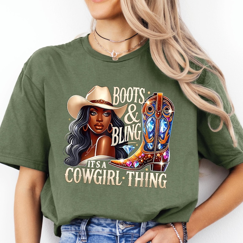 K&ouml;nnte beinhalten: Olivgr&uuml;nes T-Shirt mit einer Grafik einer Frau mit Cowboyhut und einem verzierten Cowboy-Stiefel. Der Text auf dem Shirt lautet "Boots & Bling, It's a Cowgirl Thing."