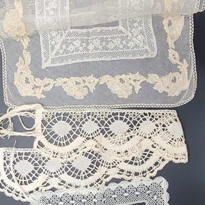 May include: Assortment of antique lace textiles in various designs. Includes a large rectangular piece with floral and geometric patterns, a scalloped edge trim, and a square frame. The lace is off-white and delicate.