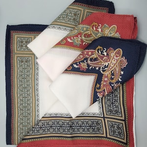 Könnte beinhalten: Vier gefaltete Einstecktücher in Rot, Marineblau und Weiß. Die Einstecktücher weisen aufwendige Paisley- und geometrische Muster auf. Die Ränder sind mit detaillierten Designs versehen. Die Einstecktücher sind aus einem weichen, wahrscheinlich Seidenmaterial.