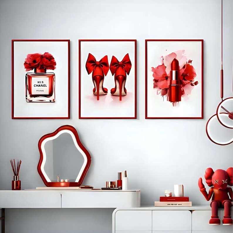 May include: Three framed art prints with red accents. One features a perfume bottle with red flowers, another shows red high heels with bows, and the third displays a lipstick with floral elements. A red mirror and decorative items complete the scene.