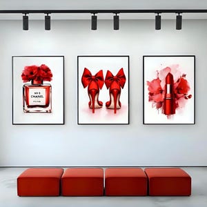 May include: Three framed art prints featuring a perfume bottle, high heels, and lipstick. The perfume bottle is red with the text "N&deg; 5 CHANEL PARIS". The high heels are red with large bow accents. The lipstick is red with a floral arrangement.