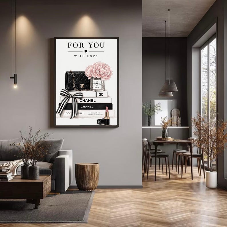 May include: A framed wall art print featuring the text FOR YOU WITH LOVE, a black quilted handbag, a glass vase with pink peonies, stacked books labeled CHANEL, a black and white striped ribbon, and a lipstick tube on a white background.