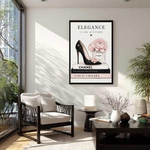May include: A framed wall art print featuring the text ELEGANCE IS AN ATTITUDE, a black quilted high-heel shoe, a pink peony flower, a perfume bottle labeled CHANEL, and a stack of three books labeled CHANEL, THE VOCABULARY OF STYLE, and COCO CHANEL.