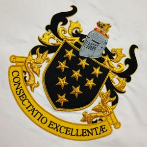 May include: Embroidered crest with a black shield featuring gold stars, a silver helmet, and gold filigree on a white background. The crest includes a yellow banner with the words "CONSECTATIO EXCELLENTE".