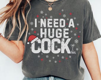May include: Dark gray t-shirt with the text "I NEED A HUGE COCK" in white block letters. A Santa hat is on the letter "C" and snowflakes and red stars surround the text. A cocktail glass graphic is on the right.