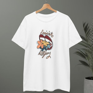 May include: White t-shirt with a graphic design featuring red lips, flowers, and the words "Feminist Killjoy" in a handwritten style. The design is centered on the front of the shirt.