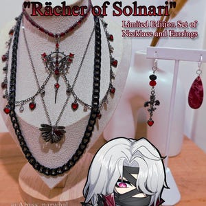 Puede incluir: Un conjunto de collar y pendientes de edición limitada. Los collares presentan cadenas negras y detalles de corazón rojo. Los pendientes incluyen un diseño de cruz y un colgante en forma de lágrima. También aparece el texto "RERIR Rächer of Solnari".