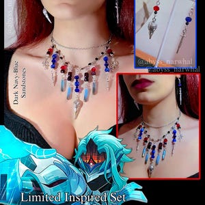 May include: A necklace and earring set with a silver chain necklace adorned with red, blue, and black beads, and dangling crystal and metal charms. The earrings have matching charms. The text "Dark Navy-Blue Sandstones" is visible.