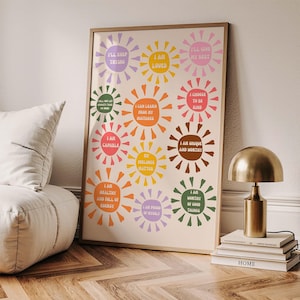 May include: A framed poster with a beige background features colorful sunburst designs, each containing a positive affirmation in a retro font. The affirmations include phrases like "I am loved" and "I am worthy of good things."