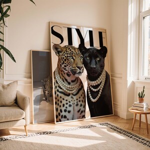 May include: A framed art print featuring a leopard and a black panther, each adorned with pearl necklaces. The word "STYLE" is printed at the top. A smaller framed print of a leopard is visible in the background.
