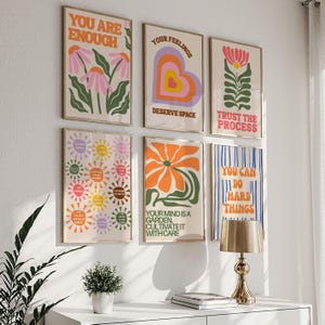 May include: A collection of six framed art prints with motivational quotes and floral designs. The prints feature phrases like "You Are Enough" and "Trust the Process" in a retro color palette of orange, pink, and green.