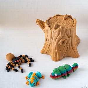 May include: A collection of colourful polymer clay figurines. Includes a brown tree stump, a black and orange spider, a blue and orange frog, and a green, red, and blue chameleon. The figurines are set against a white background.