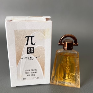 May include: A Givenchy Pi Eau de Toilette bottle and box. The box is white with gold accents and the Pi symbol. The bottle is a small, clear, geometric shape with a gold cap and contains a golden liquid. The text on the box reads "EAU DE TOILETTE POUR HOMME FOR MEN".