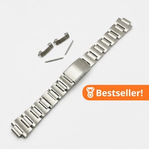 May include: A silver-toned stainless steel watch bracelet with a folding clasp featuring the Seiko logo, accompanied by two metal end links and two spring bars. An orange rectangular graphic with a medal icon and the text Bestseller! is present.