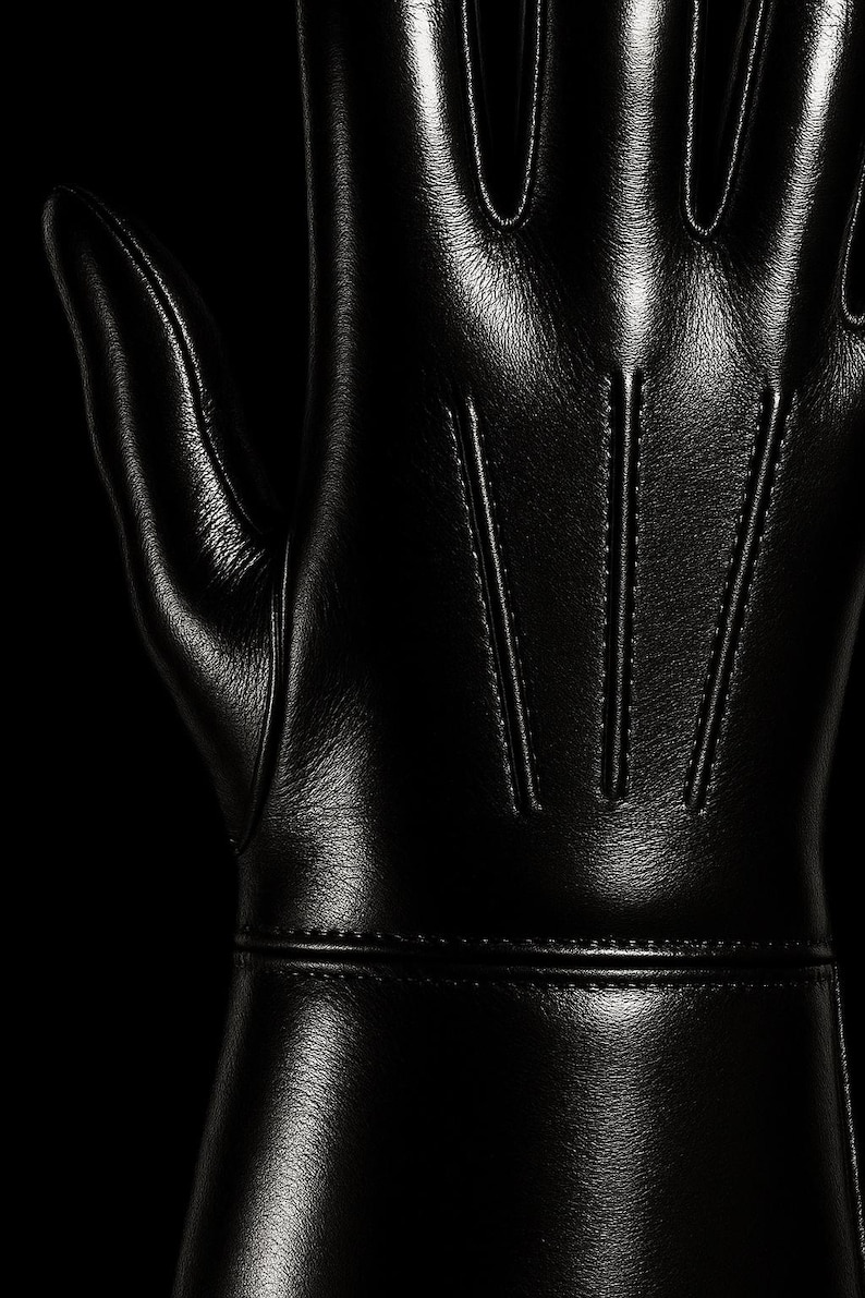 May include: Black leather gloves with a smooth, shiny finish. The gloves have a seam down the center of each finger and a seam around the wrist.