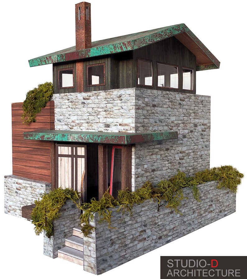 K&ouml;nnte beinhalten: Ein Modell eines kleinen, modernen Hauses mit einer Steinfassade, einem gr&uuml;nen Dach und einer Holzt&uuml;r. Das Haus hat eine kleine Veranda mit einer Treppe, die zur T&uuml;r f&uuml;hrt. Das Haus ist von einer Steinmauer umgeben, auf der gr&uuml;nes Moos w&auml;chst. Der Text "STUDIO-D ARCHITECTURE" ist unten im Bild gedruckt.