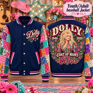 May include: A navy blue baseball jacket featuring a patchwork-style pattern on the sleeves and back. The front displays the text Dolly. The back features a graphic of a woman with blonde hair, the text Dolly, 1946, 2026, and Coat of Many Colors.