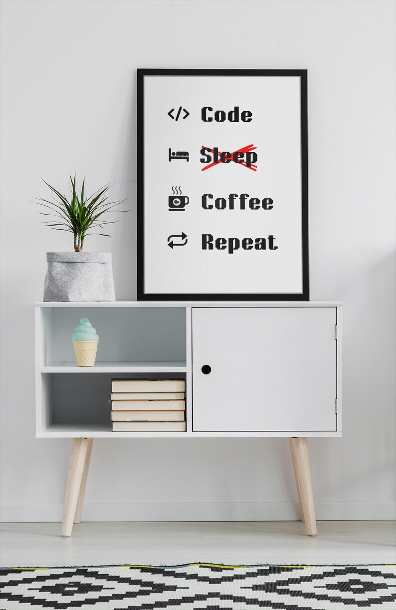 Pode incluir: Um arm&aacute;rio branco com uma porta preta e duas prateleiras. A prateleira superior tem um cone de sorvete azul e branco. A prateleira inferior tem uma pilha de livros. Um p&ocirc;ster preto emoldurado com texto branco diz "Code Coffee Repeat" com uma linha vermelha atrav&eacute;s da palavra "Sleep". Uma planta verde em um vaso cinza est&aacute; em cima do arm&aacute;rio.