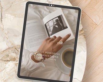 Peut inclure: Une tablette affichant un livre avec le texte "Daily Powerful Affirmations for Women". La tablette est posée sur une surface en marbre blanc.