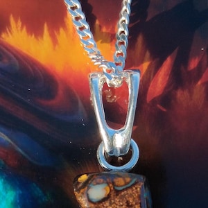May include: A silver chain necklace with a pendant featuring a brown and iridescent opal stone. The opal has a rough, textured surface with flashes of green, blue, and orange.