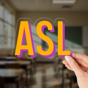 May include: A clear sticker featuring the letters ASL in a bold, sans-serif font. The letters are colored in bright yellow with a purple drop shadow, creating a layered effect. The sticker has a transparent border that follows the shape of the text.