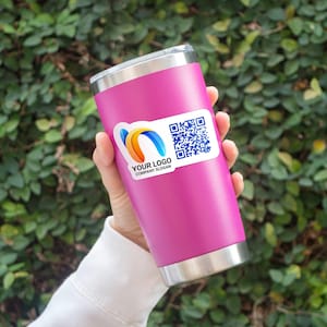 May include: A pink insulated tumbler with a silver rim and base. A white sticker with a logo and QR code is affixed to the tumbler. The logo features blue, orange, and yellow curved shapes. The text on the sticker reads "YOUR LOGO COMPANY SLOGAN."