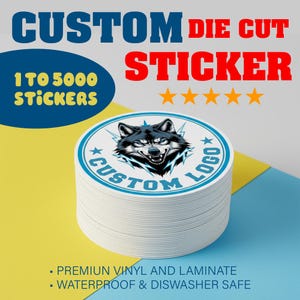 May include: A stack of white, die-cut stickers with a custom logo featuring a wolf's head. The stickers are round with a blue border and text. The image includes the text "CUSTOM DIE CUT STICKER" and "1 TO 5000 STICKERS".