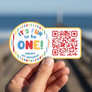 May include: A circular and rectangular sticker featuring a colorful border and the text IT'S FUN to be ONE! BAKER'S 1ST BIRTHDAY! in blue, red, and yellow. The rectangular section contains a red QR code on a white background with a yellow border.