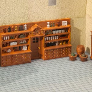 May include: A miniature brown wooden shop interior featuring a central door with a clock above, flanked by shelving units filled with tiny bottles, jars, and containers. A separate tall shelf, a wooden barrel, and two small baskets are placed nearby.