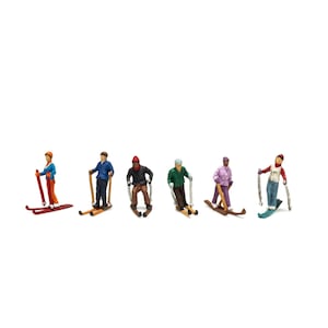 May include: A set of six miniature figurines depicting individuals in winter sports attire, each equipped with skis and poles. The figures are dressed in various colored jackets and pants, including blue, red, green, and purple, standing in a line.