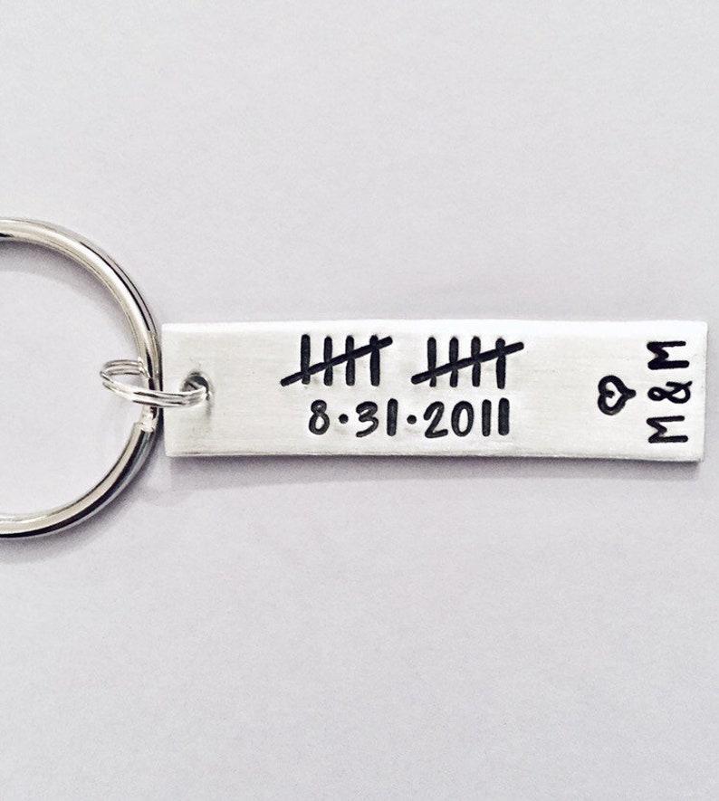 May include: Silver keychain with a rectangular tag engraved with tally marks, the date 8-31-2011, and the initials M&M with a heart symbol.