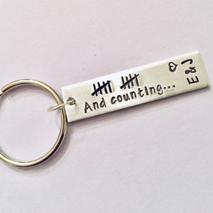 May include: Silver keychain with a silver tag that reads "And counting..." with tally marks and "E & J" with a heart symbol.