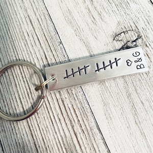 May include: Silver keychain with a rectangular tag engraved with tally marks and the text "B&G" with a heart symbol.